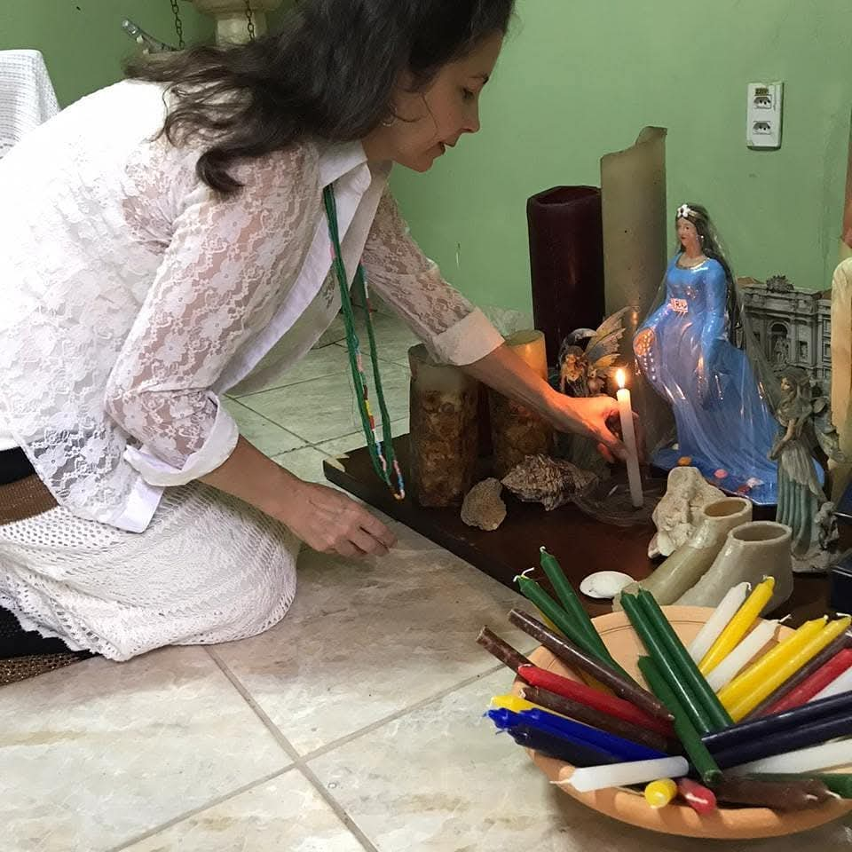 Mãe Mirian acendendo uma vela em seu altar